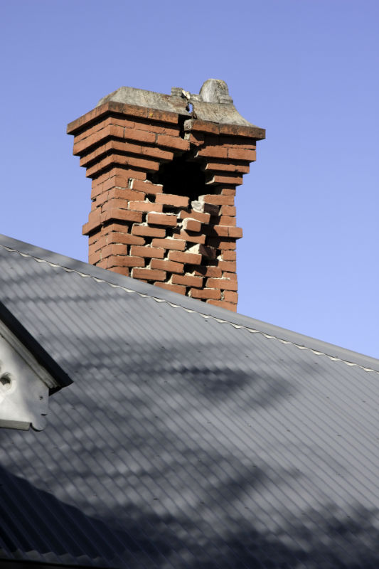 Damaged chimney with missing masonry and broken crown